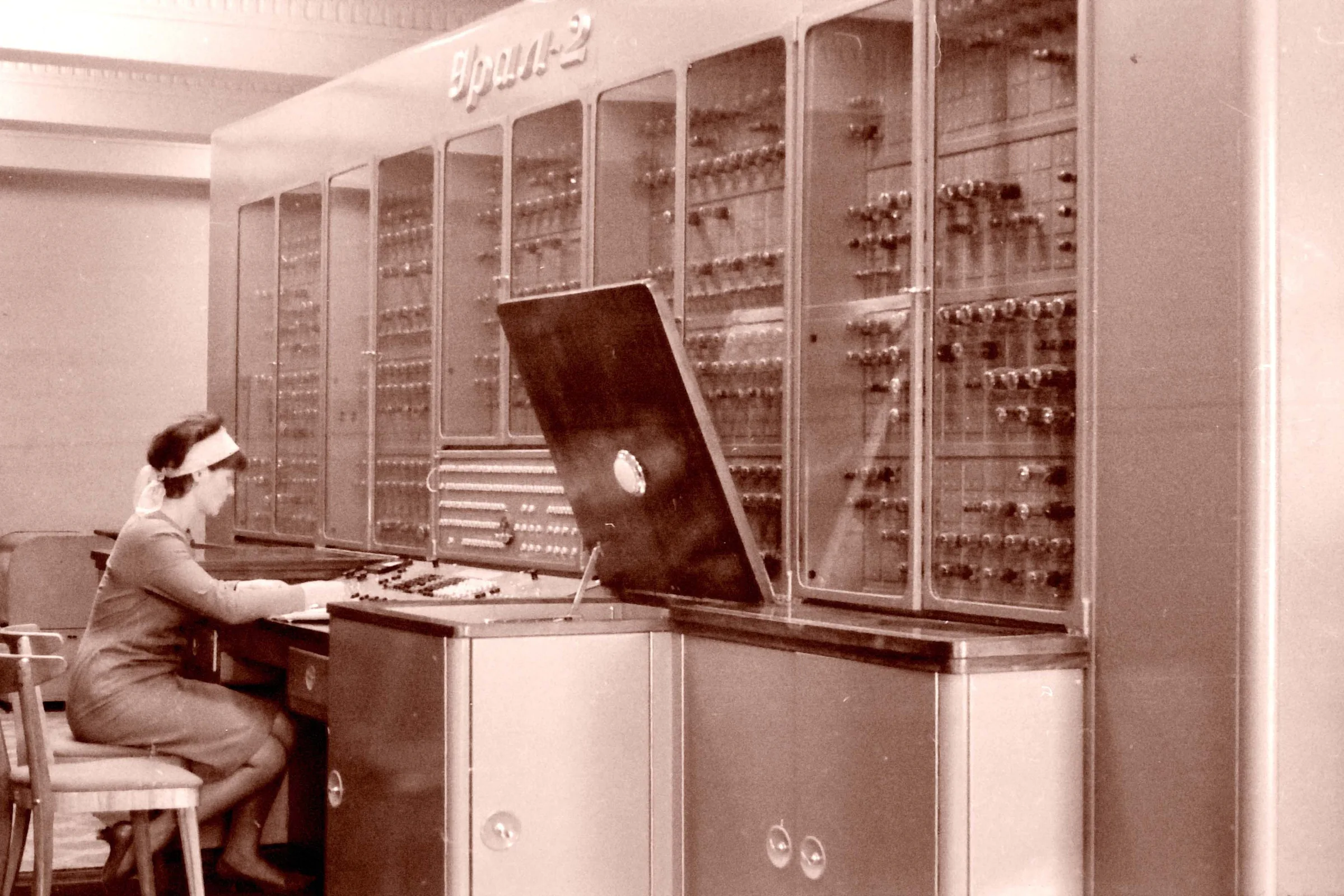 Computer operator working beside an early mainframe system