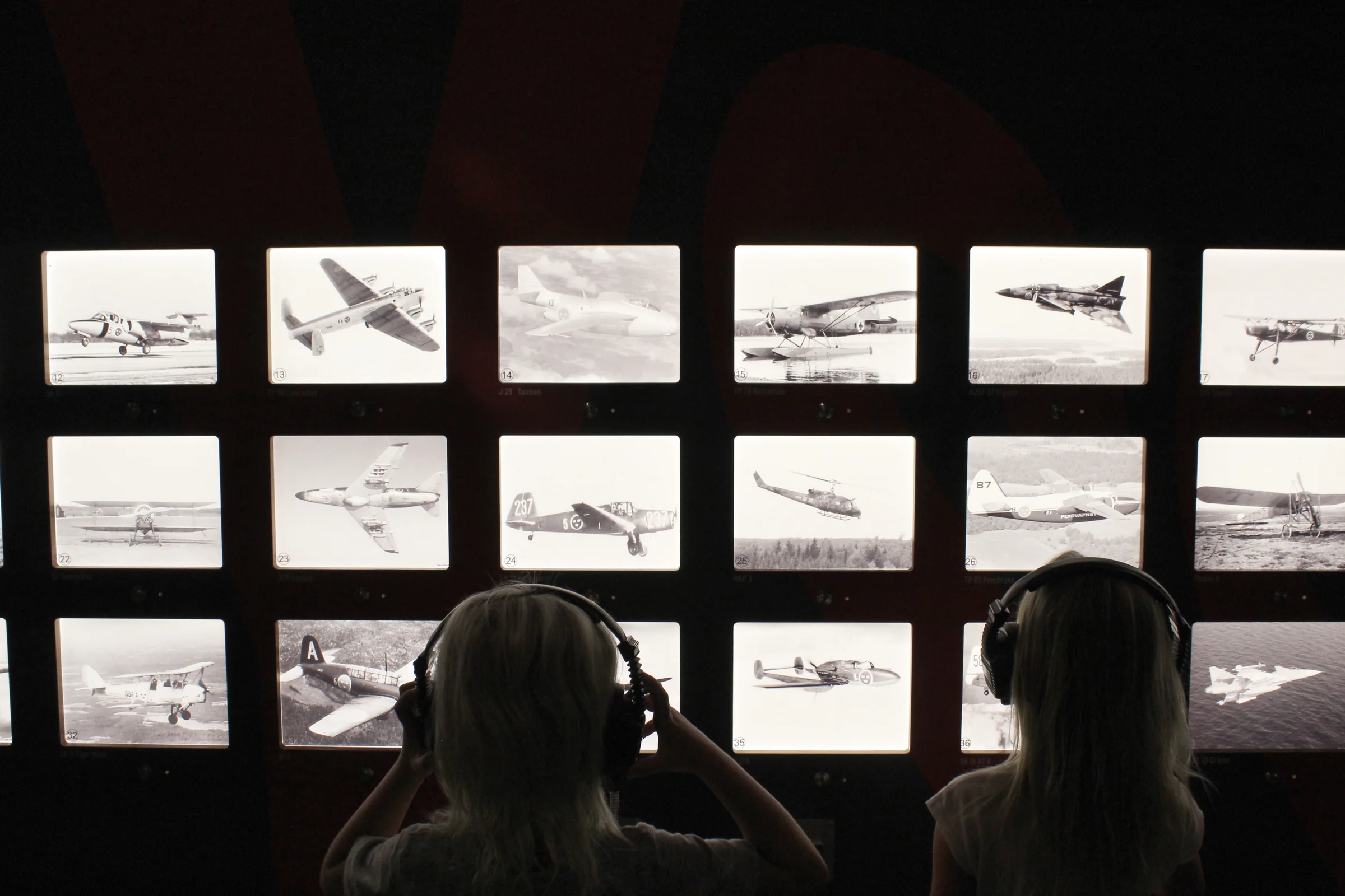 Visitors reviewing aircraft images in a museum archive
